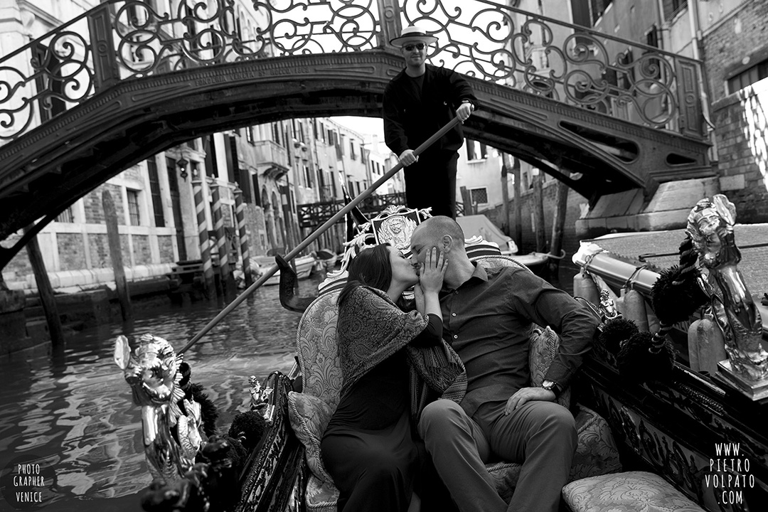 A couple kissing during a gondola ride. A photo part of an engagement photography session in Venice.