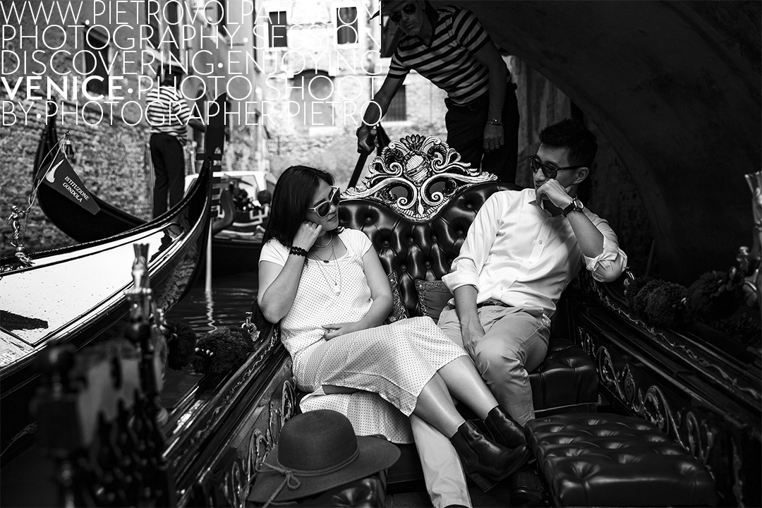 A couple enjoying a gondola ride along a narrow canal in Venice. A photo of a Venice portrait photo shoot by local photographer Pietro Volpato.