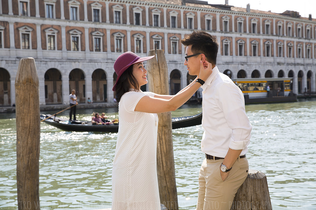 A couple having a great time on a dock along the Grand Canal in Venice. A picture of a Venice vacation photo shoot by portrait photographer Pietro Volpato.